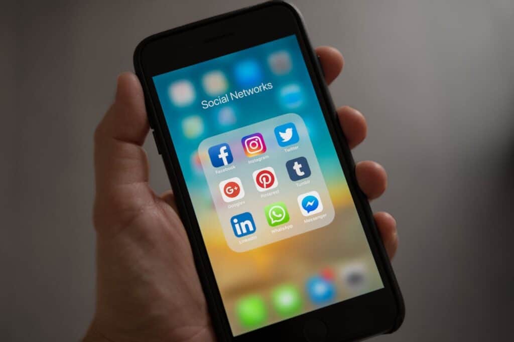 Hand holding a smartphone with social media apps on screen