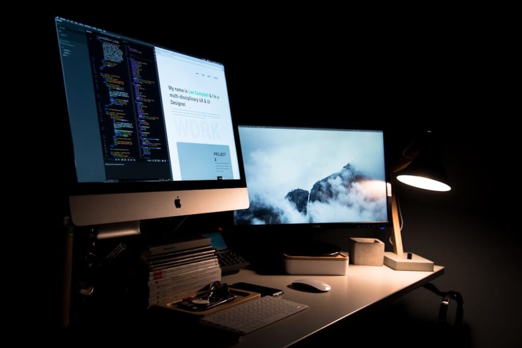 Web designer workspace with dual monitors showing a website design in progress