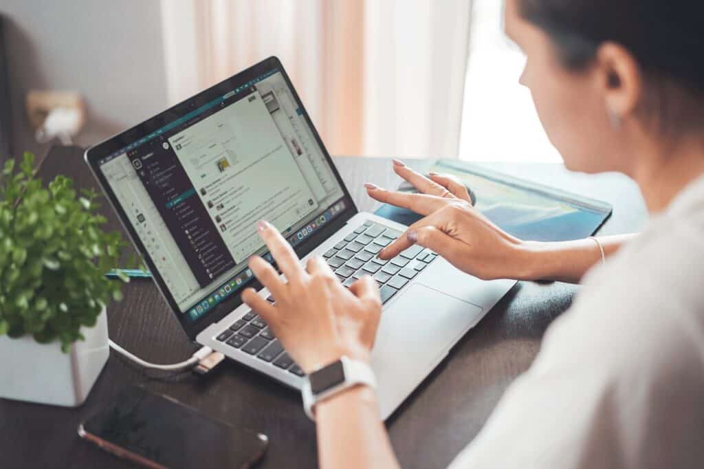 Person working on a laptop with a tablet and notebook at a desk